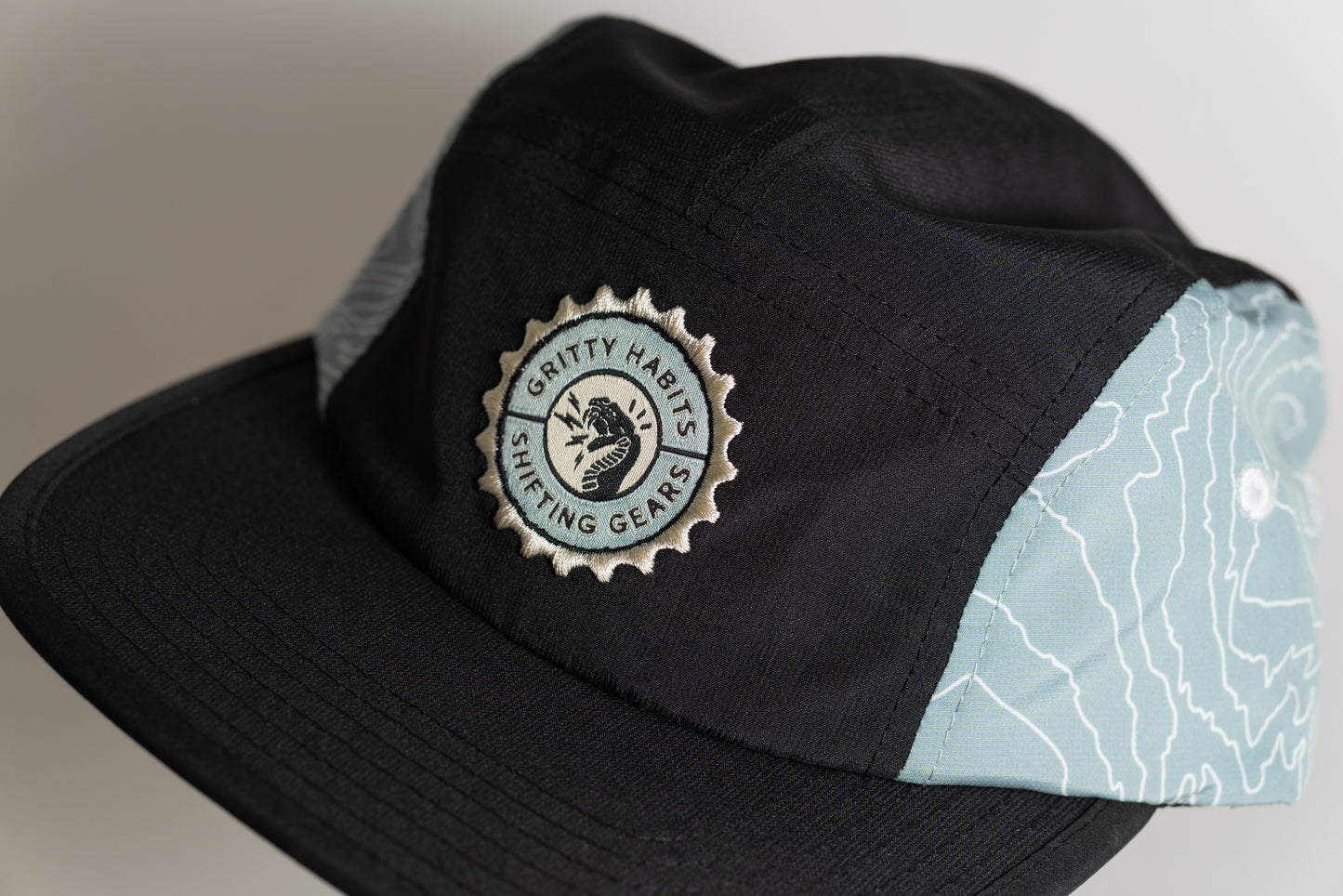Black cap with a logo on a gray background