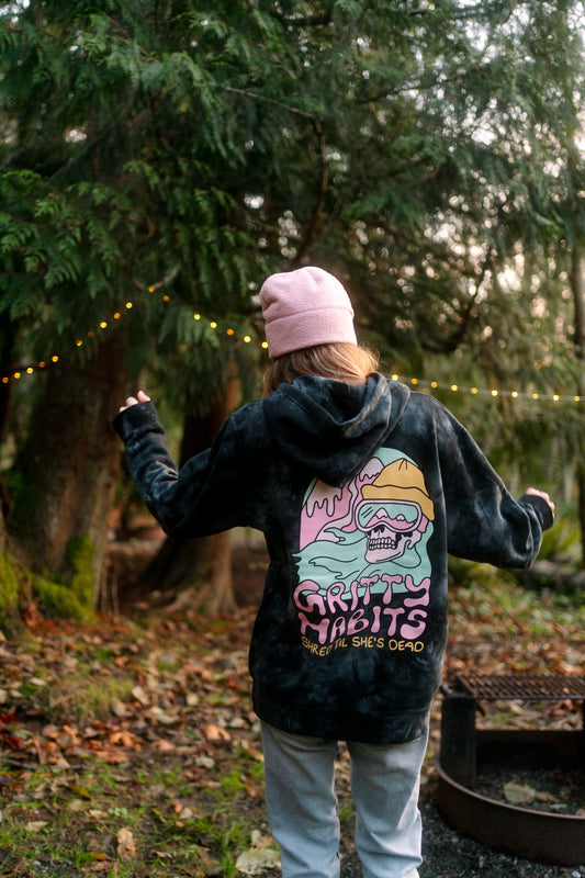 Person wearing a black hoodie with a colorful graphic design in a forest setting